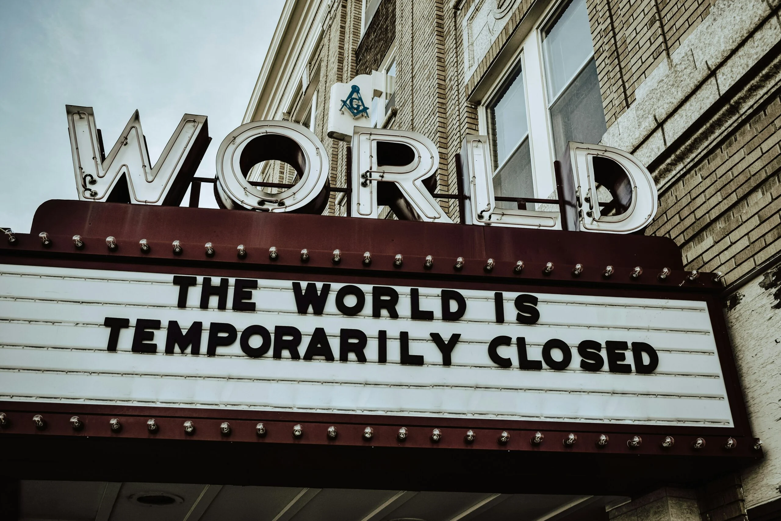 Marquee sign on a building reads "the world is temporarily closed" with large "WORLD" letters above it.