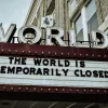 Marquee sign on a building reads "the world is temporarily closed" with large "WORLD" letters above it.